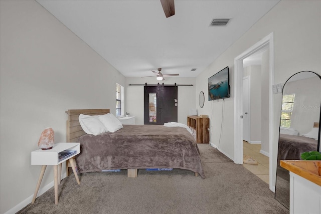 bedroom featuring multiple windows, a barn door, light carpet, and ceiling fan