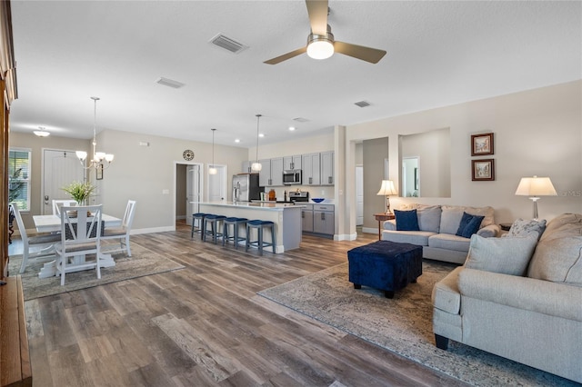 living room featuring ceiling fan with notable chandelier and hardwood / wood-style floors