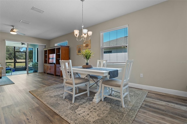 dining room with dark wood-type flooring and ceiling fan with notable chandelier