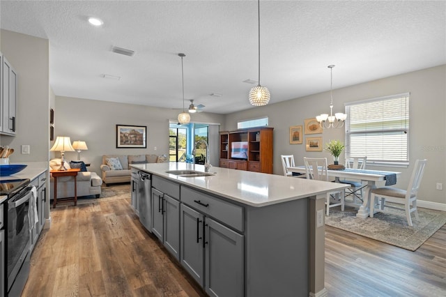 kitchen featuring gray cabinets, decorative light fixtures, sink, a kitchen island with sink, and stainless steel appliances