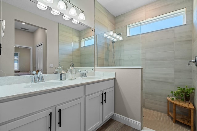 bathroom featuring tiled shower, plenty of natural light, hardwood / wood-style floors, and vanity