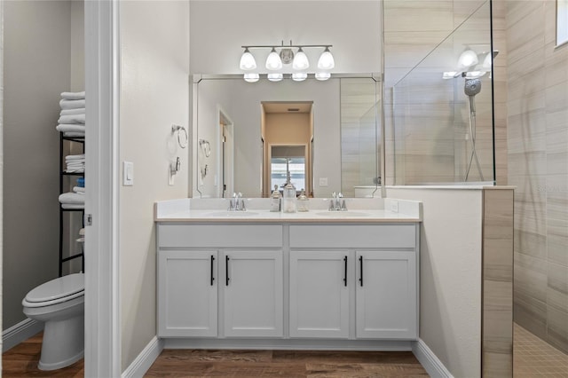 bathroom featuring vanity, hardwood / wood-style floors, toilet, and tiled shower