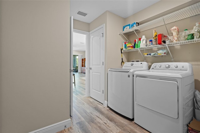 washroom featuring washing machine and clothes dryer and light hardwood / wood-style flooring