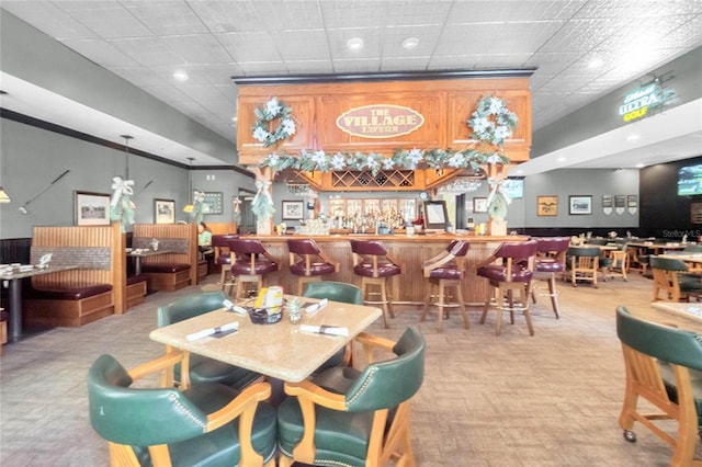 carpeted dining area featuring a paneled ceiling and indoor bar