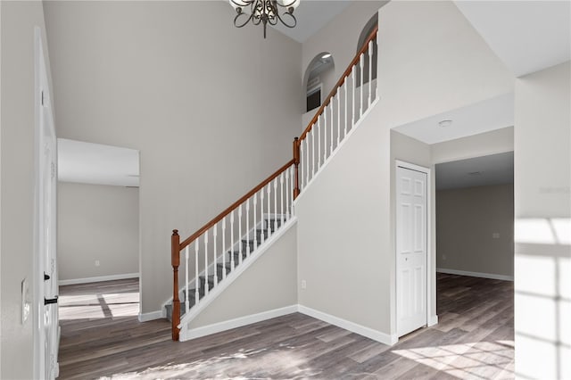 staircase with a high ceiling, hardwood / wood-style floors, and a notable chandelier