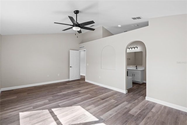 empty room with ceiling fan, lofted ceiling, sink, and light hardwood / wood-style flooring