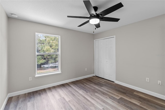 unfurnished bedroom with ceiling fan, hardwood / wood-style floors, and a closet