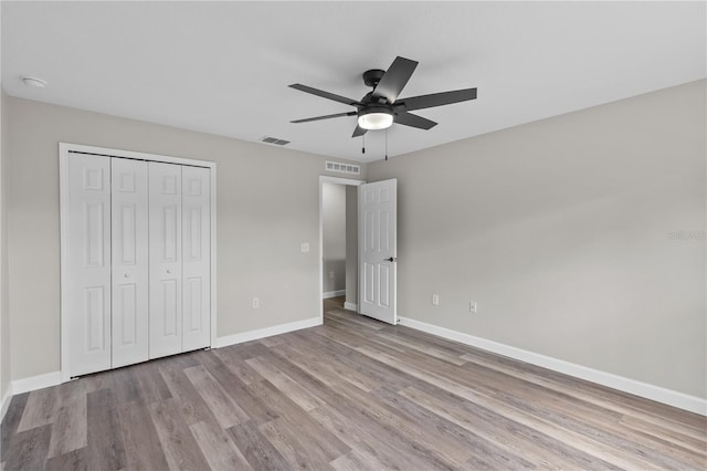 unfurnished bedroom with light hardwood / wood-style flooring, a closet, and ceiling fan