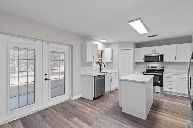 kitchen with appliances with stainless steel finishes, sink, a kitchen island, and white cabinets