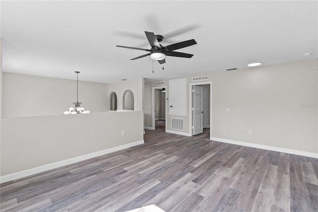 spare room with ceiling fan with notable chandelier and light wood-type flooring