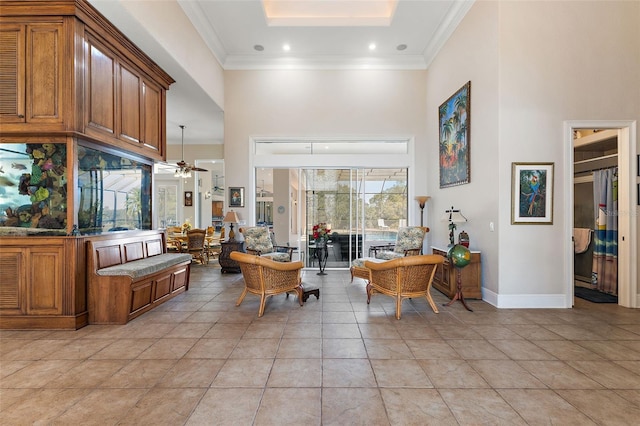 interior space featuring light tile patterned flooring, a towering ceiling, ornamental molding, and ceiling fan