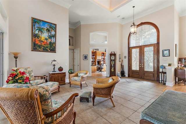 foyer entrance with french doors, a chandelier, light tile patterned floors, ornamental molding, and a high ceiling