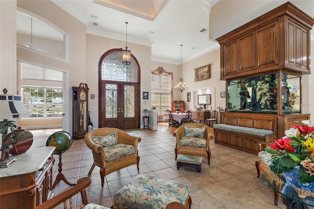 interior space with a towering ceiling, ornamental molding, french doors, and a chandelier