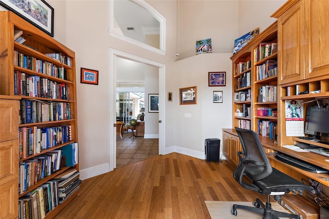 office with a high ceiling and hardwood / wood-style floors