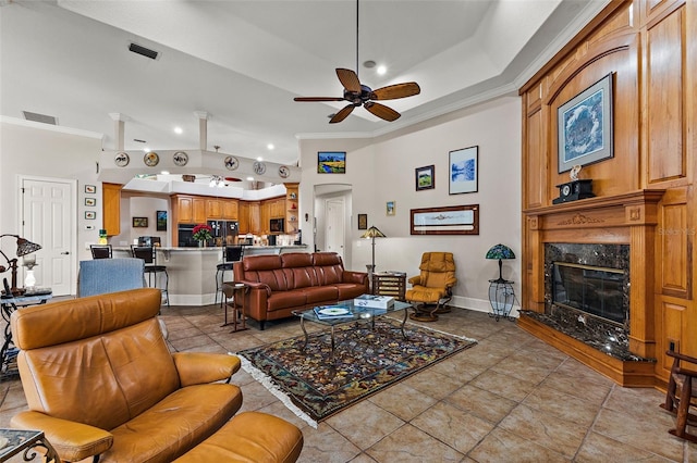 tiled living room with crown molding, ceiling fan, and a fireplace