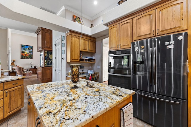 kitchen featuring light stone countertops, crown molding, black appliances, and a center island