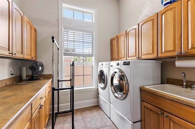 washroom featuring sink, light tile patterned floors, washer and clothes dryer, and cabinets