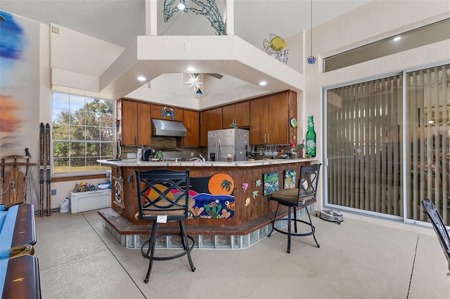 kitchen with stainless steel fridge, a kitchen bar, and kitchen peninsula