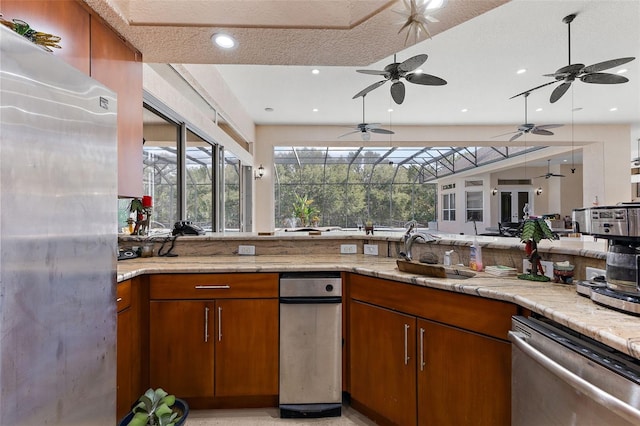 kitchen featuring sink, stainless steel dishwasher, a textured ceiling, and light stone counters