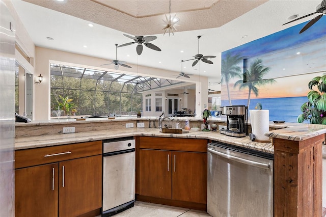 kitchen featuring sink, a water view, dishwasher, kitchen peninsula, and light stone countertops