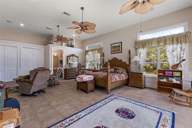 tiled bedroom featuring multiple closets, ceiling fan, and multiple windows