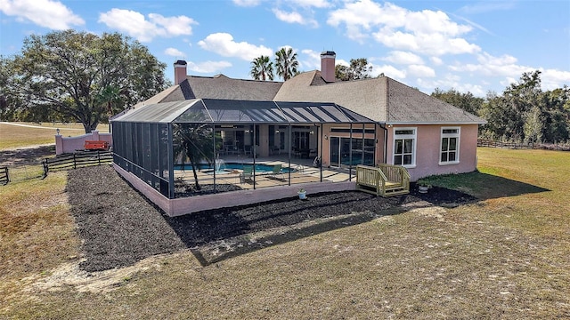 rear view of house with a lanai, a lawn, and a patio