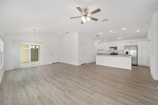 unfurnished living room with sink, ceiling fan with notable chandelier, vaulted ceiling, and light wood-type flooring