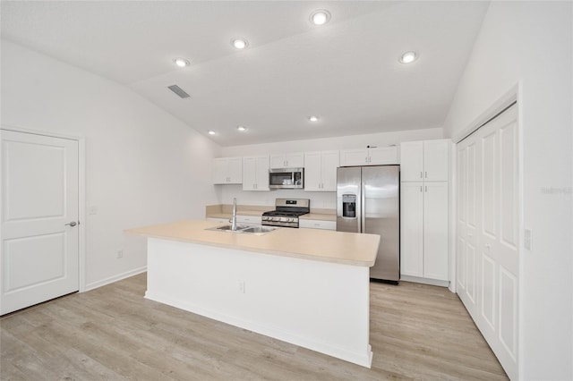 kitchen with sink, white cabinetry, vaulted ceiling, appliances with stainless steel finishes, and a kitchen island with sink