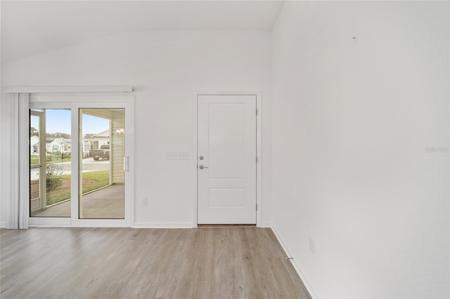 empty room with lofted ceiling and light wood-type flooring