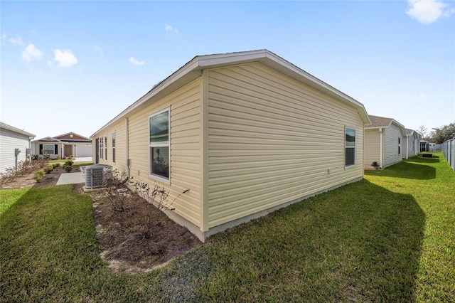 view of side of property featuring central AC and a lawn