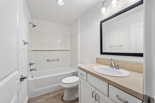 full bathroom featuring tiled shower / bath combo, vanity, wood-type flooring, a textured ceiling, and toilet