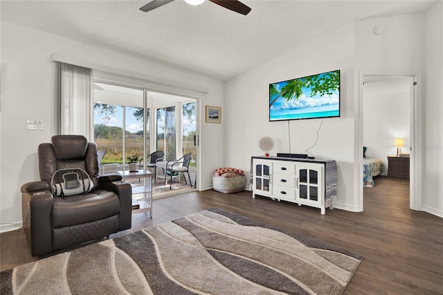 living room featuring lofted ceiling, ceiling fan, dark wood-type flooring, and a textured ceiling