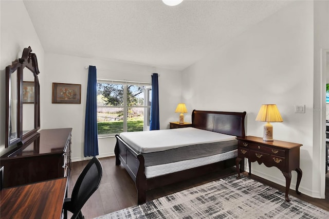 bedroom with dark hardwood / wood-style floors and a textured ceiling