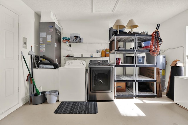 laundry area with a textured ceiling, electric water heater, and washing machine and clothes dryer