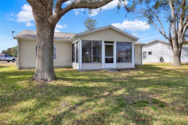 rear view of house featuring a sunroom and a yard