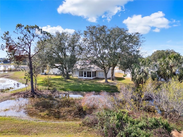 view of yard featuring a sunroom and a water view