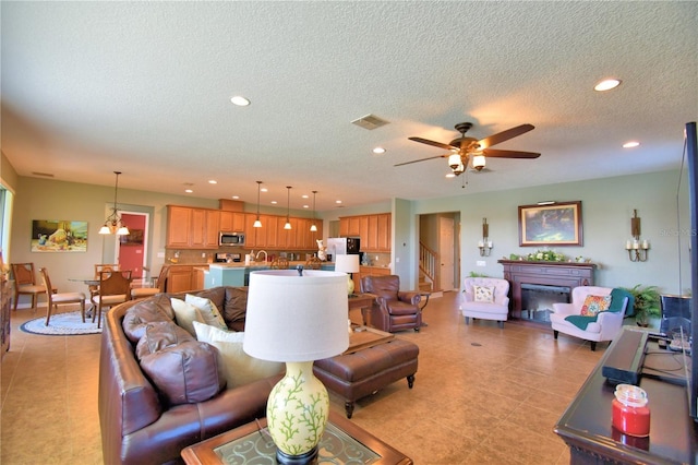 living room featuring ceiling fan, a textured ceiling, and light tile patterned flooring