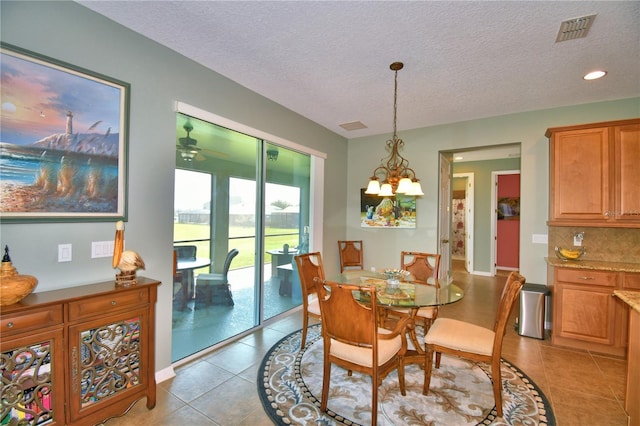 tiled dining room featuring a notable chandelier and a textured ceiling