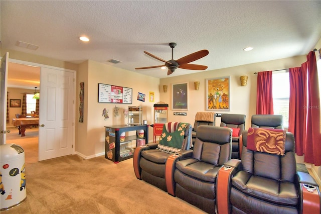 home theater featuring ceiling fan, light colored carpet, and a textured ceiling