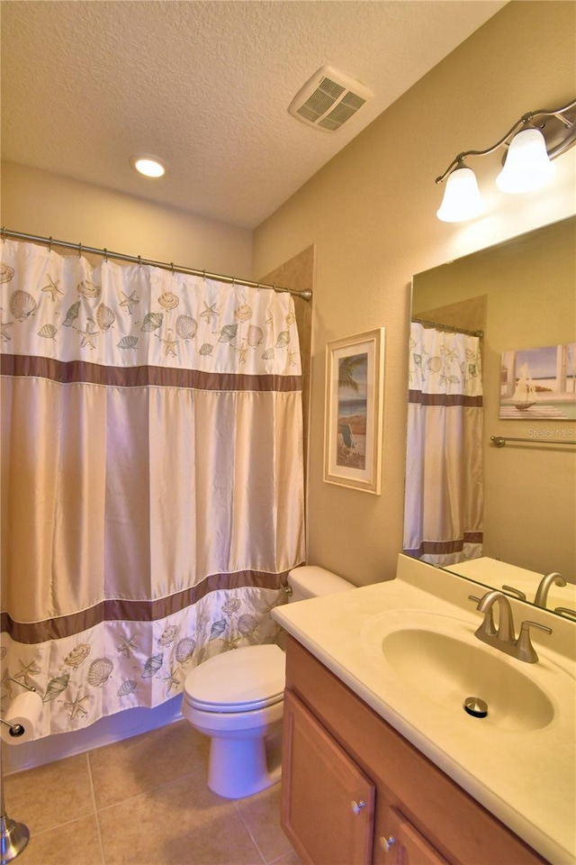 bathroom featuring vanity, toilet, tile patterned flooring, and a textured ceiling