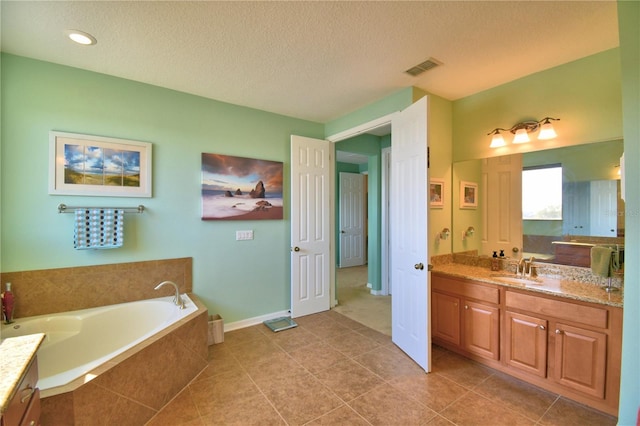 bathroom featuring vanity, tile patterned flooring, a relaxing tiled tub, and a textured ceiling