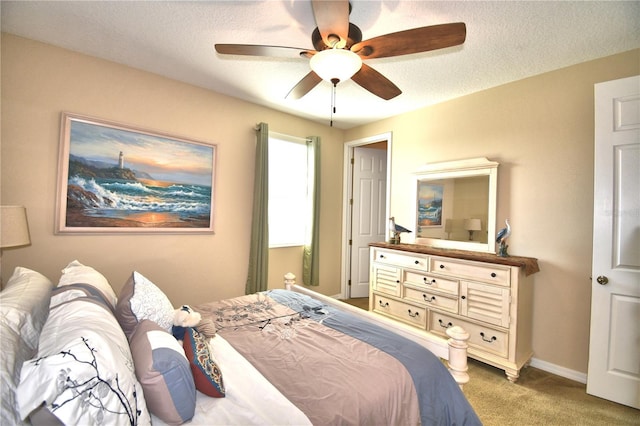 bedroom with ceiling fan, carpet, and a textured ceiling