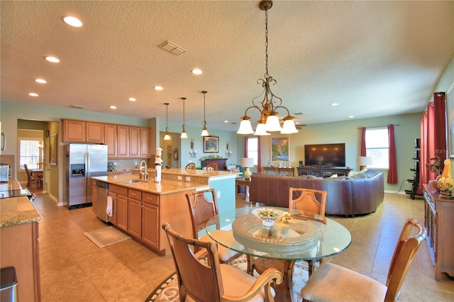 dining space with sink, a notable chandelier, and a textured ceiling