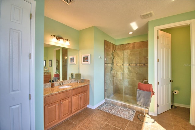 bathroom with an enclosed shower, vanity, tile patterned floors, and a textured ceiling