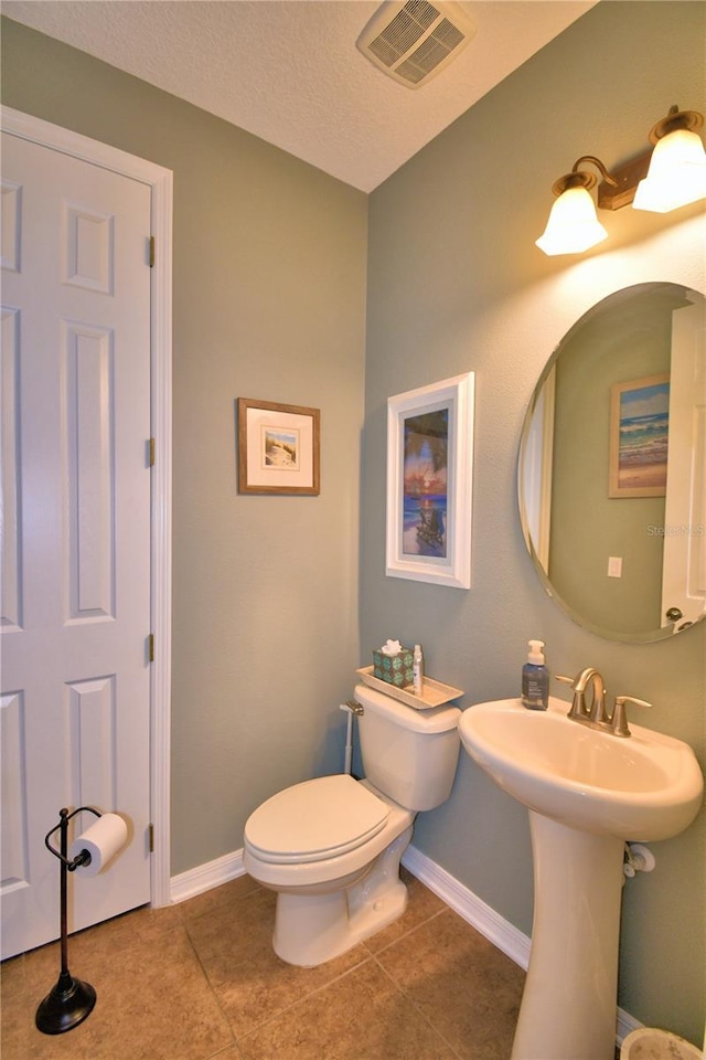 bathroom featuring sink, toilet, tile patterned flooring, and a textured ceiling