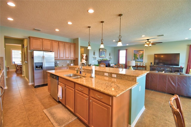 kitchen with stainless steel appliances, an island with sink, hanging light fixtures, and sink