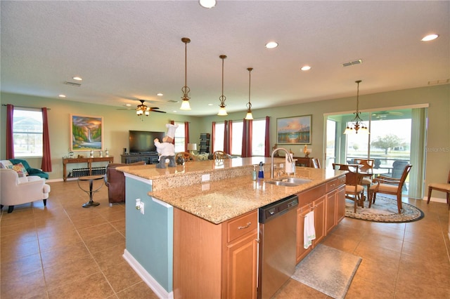 kitchen featuring stainless steel dishwasher, sink, light stone countertops, and a kitchen island with sink