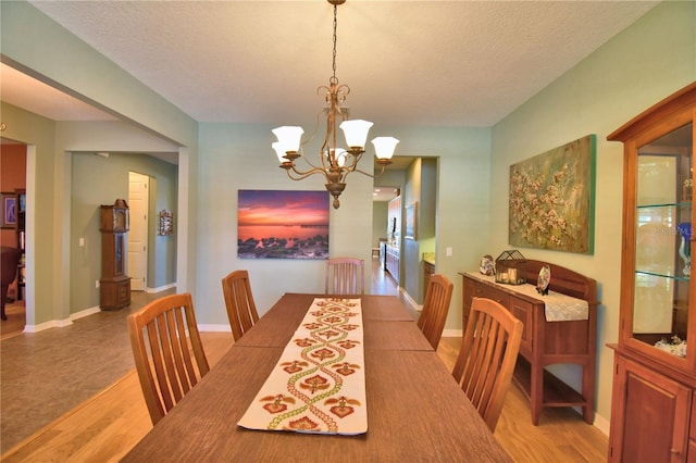 dining space featuring a textured ceiling, a notable chandelier, and light wood-type flooring