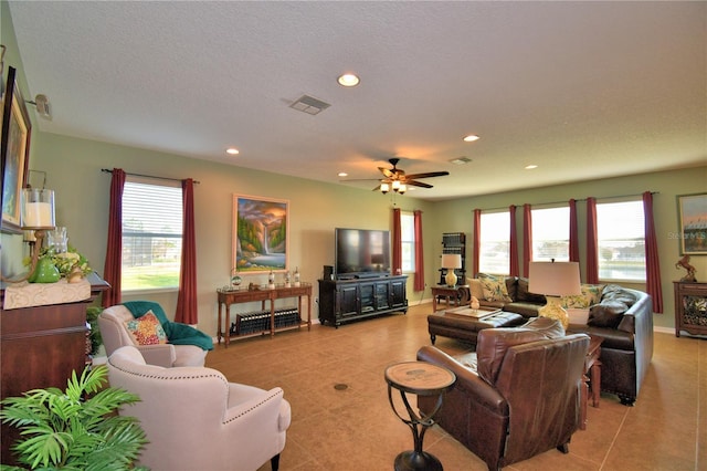 tiled living room featuring ceiling fan, a wealth of natural light, and a textured ceiling