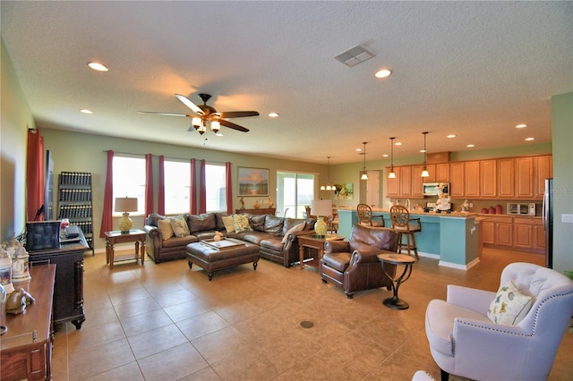 living room featuring ceiling fan, a textured ceiling, and light tile patterned floors